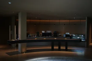 Inviting cafe with a long counter and chairs, featuring cups, bowls, and bottles, in a relaxed atmosphere