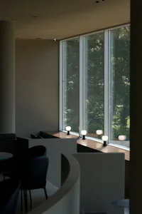 Bright dining room with large windows, two chairs, and three dining tables, with a warm and inviting atmosphere