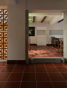 Warm and inviting kitchen space with red tile flooring, a dining table, chairs, and a potted plant