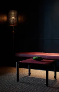 Darkened living space with a red bench, a bowl of green vegetables, and a cozy atmosphere