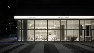 A well-lit coffee shop with tables, chairs, and a large window allowing natural light to enter