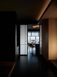 Elegant dining space with a table, chairs, and a vase, surrounded by a large window allowing natural light to enter