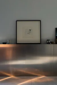 Decorative wall with a large picture and a smaller one below, accompanied by three bowls on a surface in front of it
