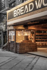 溫暖親切的麵包店內部，木質櫃檯、磚牆，以及新鮮烘焙麵包的招牌