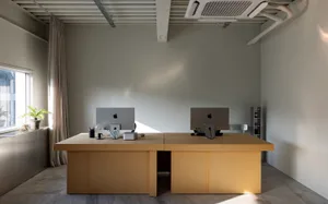 Modern office workspace with two desks, chairs, and books on a wooden floor