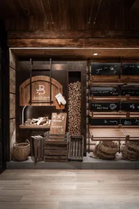 Industrial showroom with wooden walls and flooring, featuring signs, furniture, and baskets