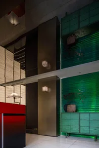 A modern interior space with a red wall, green tiles, glass dividers, and lush plants creating a lively atmosphere
