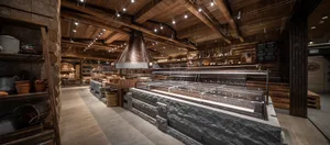 Warm and inviting restaurant interior with a large stone wall, brick oven, and comfortable seating areas