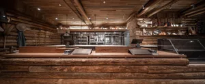 Warm and inviting kitchen with wooden floors and walls, featuring a refrigerator, oven, and multiple appliances, with a cozy ambiance created by natural wood elements