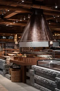 Cozy restaurant dining area with a large stone oven, wooden elements, and stone walls, featuring a central fireplace