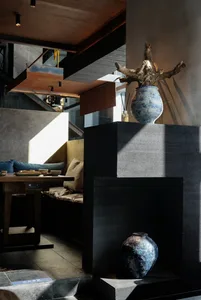 Cozy living space with a black couch, vases, and bowls, and a dining table in the background