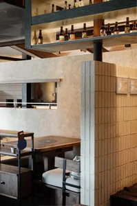 Cozy restaurant interior with brick walls, tables, chairs, and bottles, creating a warm and inviting atmosphere