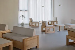 Empty minimalist room with a white couch, chairs, and a potted plant, featuring a clean and minimalistic atmosphere