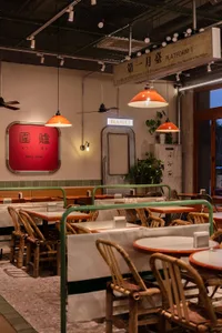 Cozy Asian restaurant interior with dining tables, chairs, potted plants, and oriental writing on the walls
