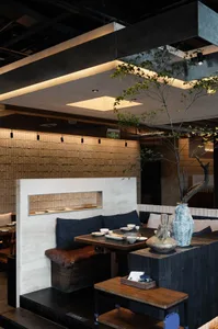 Elegant dining space with wooden tables, chairs, and accents, surrounded by plants and natural elements