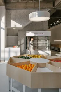 A bright and inviting store filled with bowls of fresh fruit and vegetables, with a woman browsing the selection