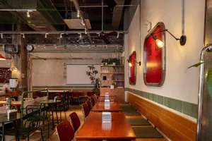 Warm and inviting Asian restaurant interior with wooden tables, red accents, and potted plants