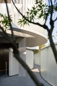 A modern building with a curved structure, surrounded by trees, in a contemporary and artistic setting