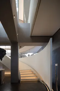A spiral staircase in a museum setting with sculptures on display, made of wood with a sense of history and artistic expression