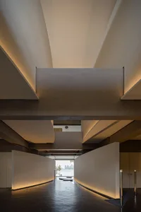 A modern interior space with high ceilings, a skylight, and concrete walls, featuring two windows on either side, allowing natural light to enter the room