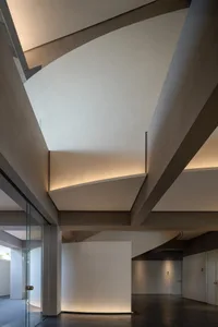 A large open interior space with high ceilings and curved design, featuring concrete walls and a modern industrial aesthetic