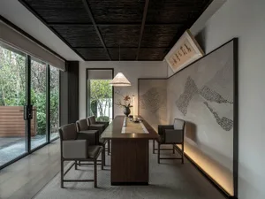 A modern dining space with a table and chairs, a vase on the table, and a well-lit atmosphere