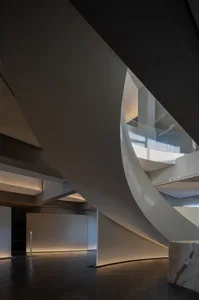 A spiral staircase with a white color scheme is surrounded by a glass enclosure in a rendered architectural scene