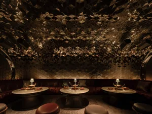 Sophisticated restaurant interior with a bar area, multiple dining tables, and comfortable seating, featuring various decorative items and a warm atmosphere