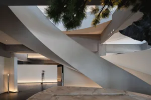 Modern building with multiple levels, concrete exterior, and a spiral staircase, featuring two people in a minimalist setting