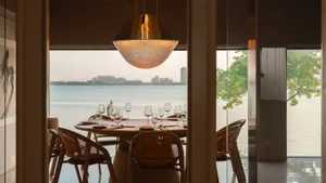 Elegant dining space with a round table, wine glasses, and bottles, surrounded by modern furniture in a well-lit room