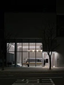 A modern dining space with a concrete floor and walls, a dining table, chairs, and warm lighting