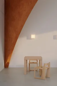 A cozy dining space with a wooden table and chairs in a minimalist white room