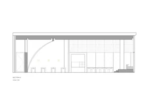 A modern commercial space with a large open area, dining area, kitchen, and chairs, suggesting a welcoming environment for visitors
