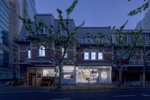 A modern Asian restaurant with large windows, second-story windows, and a city view with trees outside