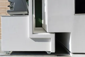 A simple interior space with a concrete wall, two windows, and a doorway, suggesting a functional design