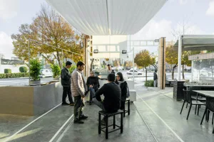 A casual dining space with a mix of wood and metal elements, featuring multiple tables and chairs, and a social atmosphere
