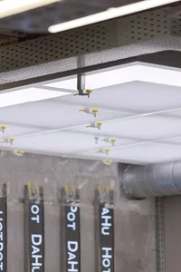 Industrial workshop with yellow-lit ceiling, hanging tools, and a well-lit environment
