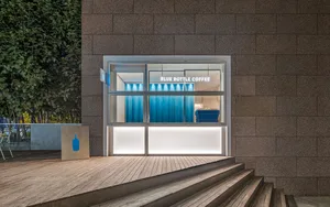A modern coffee shop with a large window, a counter, and two chairs, creating an inviting atmosphere for customers
