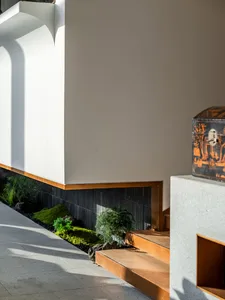 A residential or commercial space with a staircase, potted plants, and a suitcase, emphasizing functionality and organization