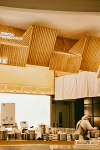 Warm and inviting kitchen dining space with wooden ceiling beams and walls, a refrigerator, dining table, and comfortable seating arrangement