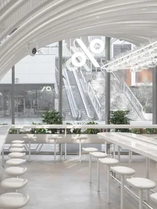 A restaurant interior with a large window, potted plants, chairs, and dining tables, creating a welcoming and comfortable atmosphere