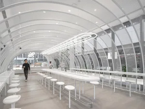 A modern restaurant interior with white tables and chairs arranged in rows, creating a clean and inviting atmosphere