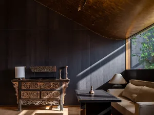 Warm and inviting living space with wooden floors and walls, two couches, and a dining table