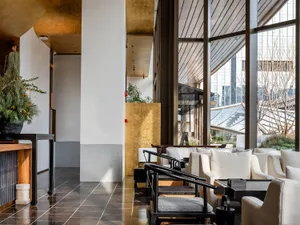 A large lobby with multiple couches, chairs, potted plants, and vases, creating a welcoming atmosphere