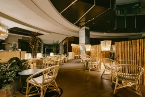 A cozy dining space with multiple chairs and tables, potted plants, and a warm atmosphere