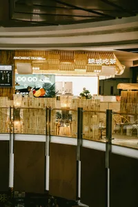 A modern cafe with a warm atmosphere, featuring wood and glass elements, chairs, dining tables, and potted plants, set in a well-lit and comfortable space