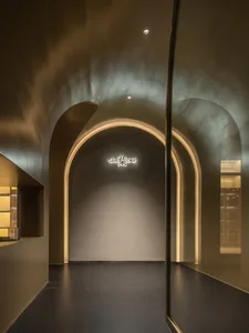 Dimly lit living space with a gold archway, a single chair, and a cozy atmosphere