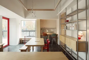 A modern kitchen with wooden floors and walls, featuring a dining table and chairs, and metal accents