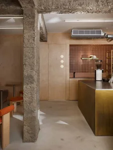 Warm kitchen space with a stone wall, wooden cabinets, and a countertop, featuring a dining table, chairs, and a sink