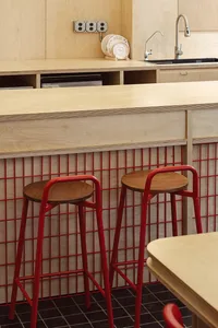 A kitchen with wooden countertops and red stools, featuring an open design and warm atmosphere with red accents
